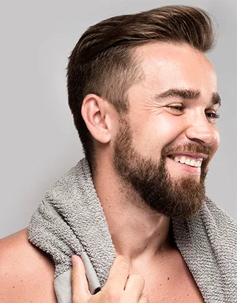 Шампоани за коса за мъже - мъж с усмивка и кърпа на врата, подготвен за грижа за косата.